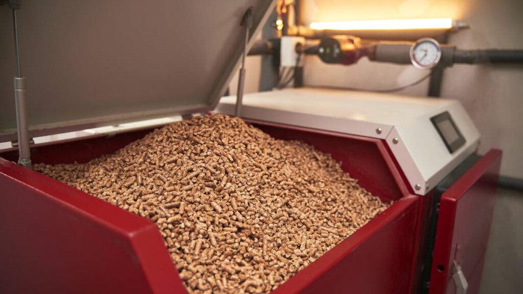 Kocioł na pellet z otwartym zasobnikiem pełnym granulatu – popularna propozycja w odpowiedzi na pytanie: „czym ogrzać stary dom?”.